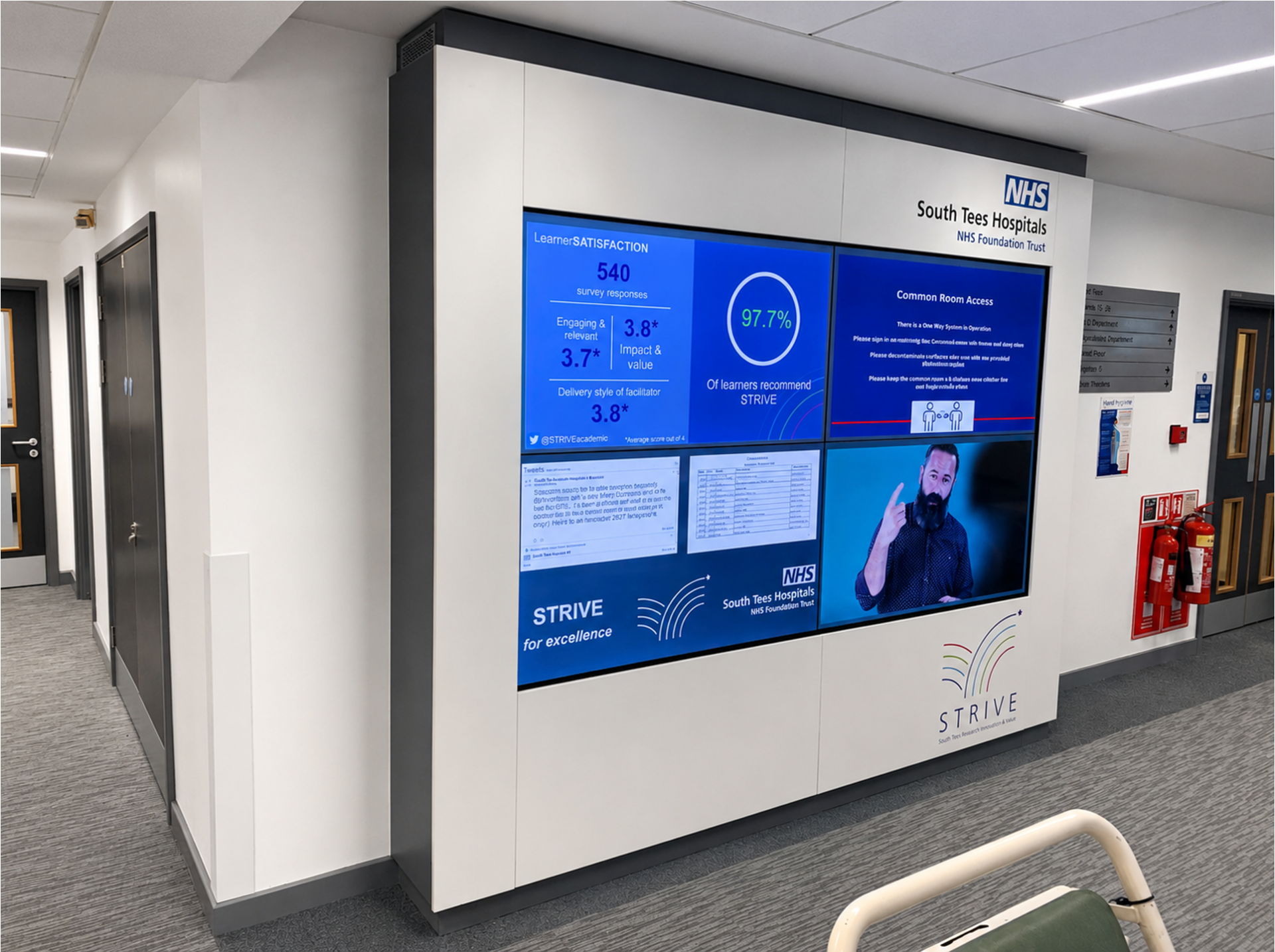 Four-screen NHS video wall in a white surround with dark grey edging and South Tees Hospitals and STRIVE branding.