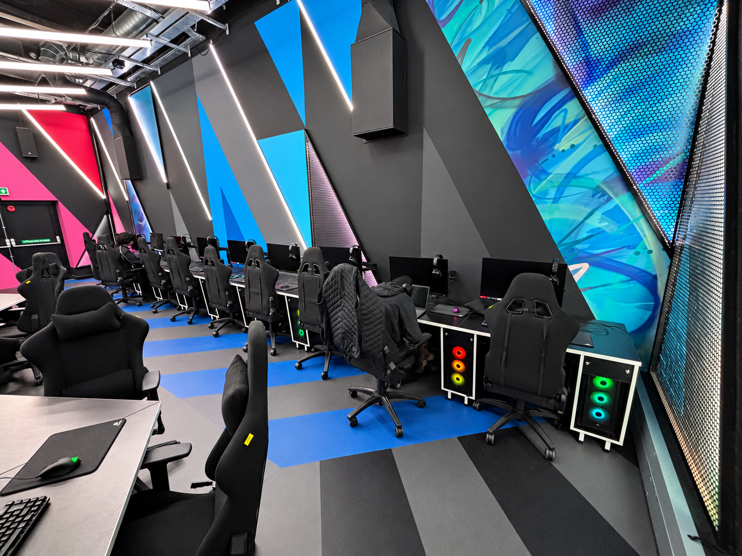 Wall-side esports desks with monitors, under-desk PC holders and gaming chairs at St Mary’s University